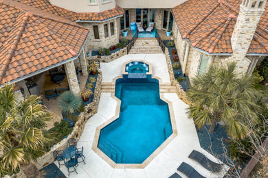 Mid-sized backyard stamped concrete and custom-shaped hot tub photo in Dallas