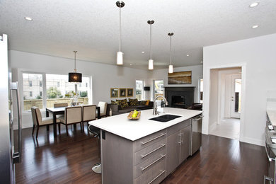 Example of a mid-sized minimalist single-wall medium tone wood floor open concept kitchen design in Calgary with an undermount sink, flat-panel cabinets, gray cabinets, quartz countertops, white backsplash, subway tile backsplash, stainless steel appliances and an island