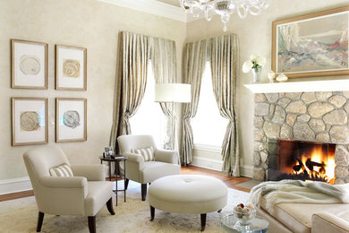 Example of a large classic enclosed and formal medium tone wood floor and brown floor living room design in New York with beige walls, a standard fireplace, a stone fireplace and no tv