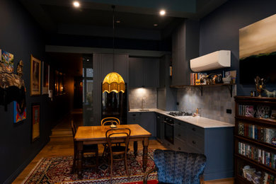 メルボルンにある高級な小さなエクレクティックスタイルのおしゃれなキッチン (アンダーカウンターシンク、シェーカースタイル扉のキャビネット、青いキャビネット、クオーツストーンカウンター、青いキッチンパネル、セラミックタイルのキッチンパネル、黒い調理設備、無垢フローリング、アイランドなし、白いキッチンカウンター、折り上げ天井) の写真