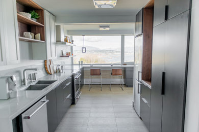 Small minimalist galley ceramic tile and beige floor enclosed kitchen photo in Vancouver with an undermount sink, flat-panel cabinets, black cabinets, quartz countertops, white backsplash, stainless steel appliances and white countertops