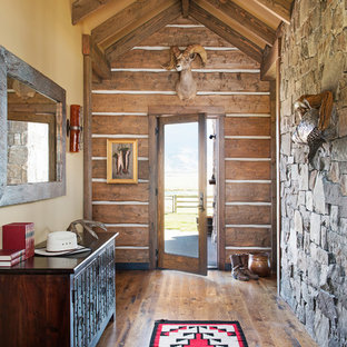 Bild på en rustik hall, med gula väggar, en enkeldörr, glasdörr och mellanmörkt trägolv