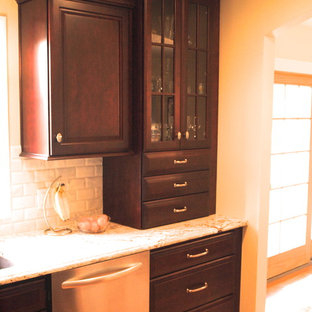 Mid-sized traditional kitchen pantry ideas - Example of a mid-sized classic l-shaped medium tone wood floor and brown floor kitchen pantry design in Newark with an undermount sink, recessed-panel cabinets, dark wood cabinets, granite countertops, beige backsplash, stone tile backsplash, stainless steel appliances and an island