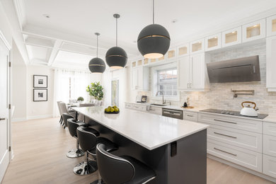 Large trendy u-shaped light wood floor and brown floor eat-in kitchen photo in Montreal with an undermount sink, shaker cabinets, white cabinets, quartz countertops, multicolored backsplash, marble backsplash, stainless steel appliances, an island and white countertops