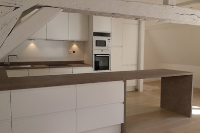 Photo of a large modern u-shaped open plan kitchen in Paris with an undermount sink, white cabinets, laminate benchtops, panelled appliances, ceramic floors, beige floor and brown benchtop.