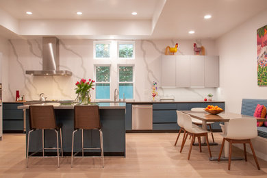 Inspiration for a contemporary l-shaped kitchen/diner in Los Angeles with flat-panel cabinets, blue cabinets, stainless steel appliances, light hardwood flooring, an island, beige floors and a drop ceiling.