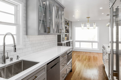 Inspiration for a small transitional galley medium tone wood floor and brown floor enclosed kitchen remodel in San Francisco with an undermount sink, shaker cabinets, gray cabinets, quartz countertops, white backsplash, ceramic backsplash, stainless steel appliances, no island and white countertops