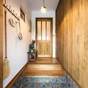 福岡の片開きドアアジアンスタイルのおしゃれな玄関 (白い壁、濃色無垢フローリング、濃色木目調のドア、マルチカラーの床) の写真