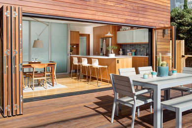Inspiration for a mid-sized contemporary galley medium tone wood floor and brown floor open concept kitchen remodel in San Diego with an undermount sink, flat-panel cabinets, medium tone wood cabinets, solid surface countertops, blue backsplash, ceramic backsplash, stainless steel appliances and an island