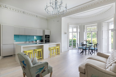 This is an example of a medium sized contemporary open plan kitchen in London with light hardwood flooring and beige floors.