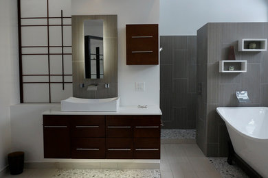 Inspiration for a large timeless master gray tile and porcelain tile pebble tile floor and gray floor bathroom remodel in Other with dark wood cabinets, gray walls, flat-panel cabinets, a trough sink and solid surface countertops