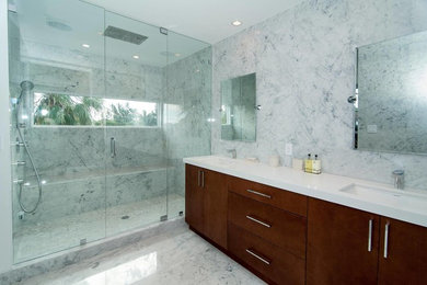 Design ideas for a mid-sized modern master bathroom in Miami with flat-panel cabinets, medium wood cabinets, an alcove shower, white tile, stone slab, white walls, marble floors, an undermount sink, quartzite benchtops, white floor and a hinged shower door.