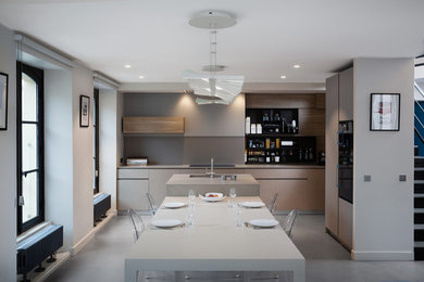 Design ideas for a modern open plan kitchen in Paris with an integrated sink, beige cabinets, solid surface benchtops, beige splashback, glass sheet splashback, concrete floors, with island, grey floor and beige benchtop.