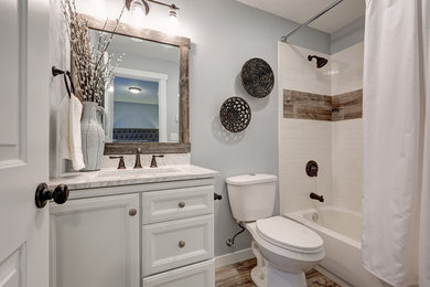 Mid-sized transitional 3/4 bathroom in Atlanta with recessed-panel cabinets, white cabinets, an alcove tub, a shower/bathtub combo, a two-piece toilet, blue walls, porcelain floors, an undermount sink, marble benchtops, beige floor, a shower curtain and white benchtops.