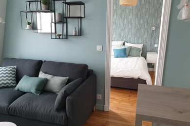 Réalisation d'une petite salle de séjour mansardée ou avec mezzanine design avec un mur bleu, parquet clair et du papier peint.
