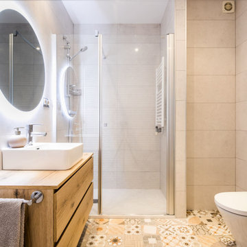 Cuarto de baño con ducha, paredes beige, encimera de madera y espejo con luz