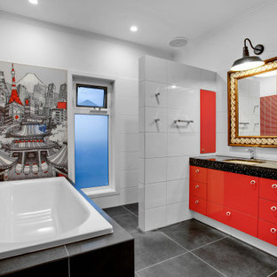 This is an example of a large eclectic master bathroom in Melbourne with flat-panel cabinets, red cabinets, a drop-in tub, an alcove shower, a one-piece toilet, white tile, porcelain tile, red walls, ceramic floors, an undermount sink, engineered quartz benchtops, black floor, an open shower, black benchtops, a niche, a single vanity and a built-in vanity.