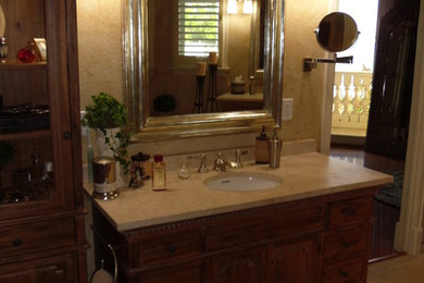 Inspiration for a mid-sized master beige tile and stone tile travertine floor bathroom remodel in Tampa with an undermount sink, furniture-like cabinets, medium tone wood cabinets, marble countertops and beige walls