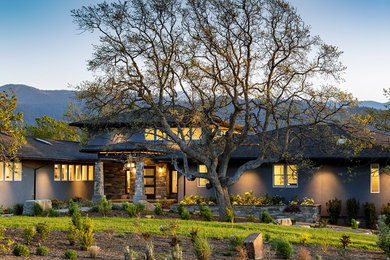Huge transitional multicolored two-story stucco house exterior photo in Other with a hip roof and a shingle roof