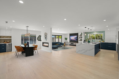 Large minimalist light wood floor and brown floor open concept kitchen photo in San Francisco with an undermount sink, flat-panel cabinets, white cabinets, quartz countertops, blue backsplash, glass tile backsplash, stainless steel appliances, an island and white countertops