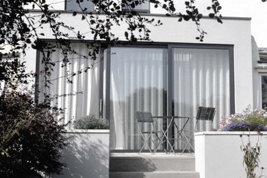 Foto de fachada contemporánea pequeña de dos plantas con revestimiento de estuco y tejado plano