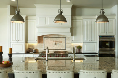 Large transitional l-shaped medium tone wood floor eat-in kitchen photo in Denver with an undermount sink, raised-panel cabinets, white cabinets, granite countertops, beige backsplash, ceramic backsplash, stainless steel appliances and an island