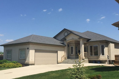 Inspiration for a mid-sized timeless beige two-story stucco exterior home remodel in Other with a shingle roof