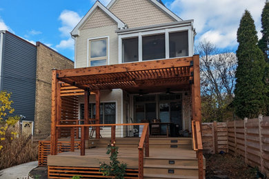 Example of a large minimalist backyard ground level cable railing deck design in Chicago with a pergola