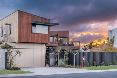 Inspiration for a beach style two-storey black house exterior in Townsville with wood siding.