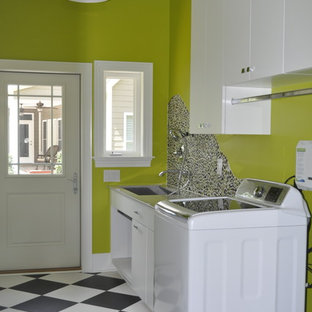 Diseño de lavadero multiusos y lineal, contemporáneo, grande, con pila para lavar, armarios con paneles lisos, puertas de armario blancas, encimera de piedra caliza, paredes verdes, suelo vinílico, lavadora y secadora juntas, suelo multicolor y encimeras multicolor
