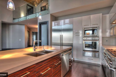Inspiration for a modern l-shaped eat-in kitchen remodel in Vancouver with an undermount sink, flat-panel cabinets, medium tone wood cabinets, solid surface countertops, white backsplash, mosaic tile backsplash and stainless steel appliances