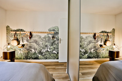 Idée de décoration pour une grande chambre parentale bohème avec un mur vert, sol en stratifié, un sol marron et du papier peint.