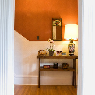 Idéer för att renovera en eklektisk entré, med orange väggar och mellanmörkt trägolv