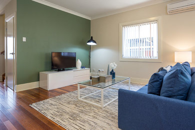 Mid-sized contemporary open concept living room in Brisbane with multi-coloured walls, dark hardwood floors and a freestanding tv.