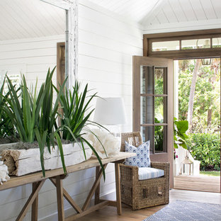 Ispirazione per un ingresso o corridoio costiero con pareti bianche, pavimento in legno massello medio, pavimento marrone, una porta singola e una porta in legno bruno