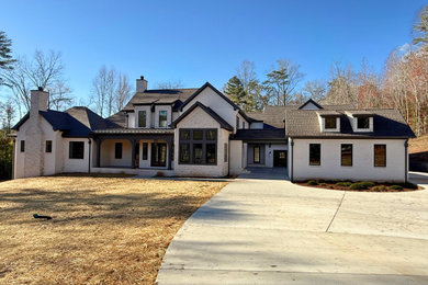 Huge transitional white two-story brick exterior home photo in Other with a mixed material roof and a brown roof