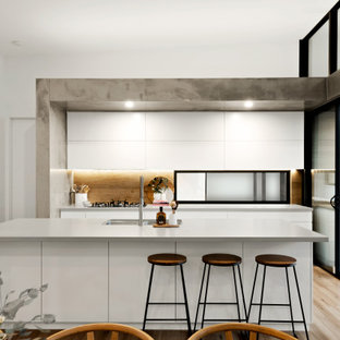 Photo of a contemporary galley kitchen in Sunshine Coast with an undermount sink, flat-panel cabinets, white cabinets, brown splashback, timber splashback, light hardwood floors, with island, beige floor and grey benchtop.