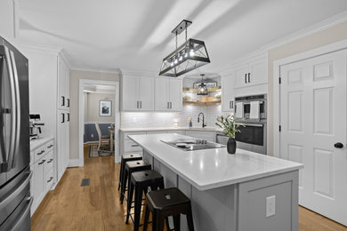 Inspiration for a mid-sized farmhouse u-shaped medium tone wood floor and brown floor enclosed kitchen remodel in Other with a single-bowl sink, shaker cabinets, gray cabinets, quartz countertops, gray backsplash, glass tile backsplash, stainless steel appliances, an island and yellow countertops