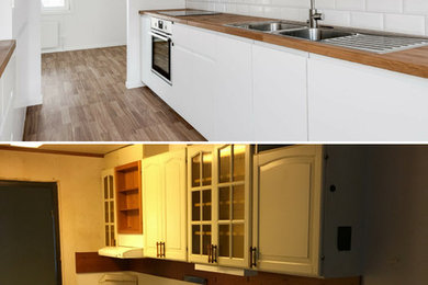Exempel på ett mellanstort klassiskt brun brunt kök och matrum, med en dubbel diskho, släta luckor, vita skåp, träbänkskiva, vitt stänkskydd, stänkskydd i trä, vita vitvaror, laminatgolv och brunt golv