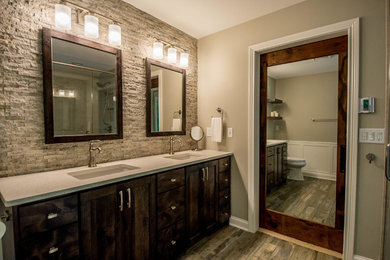 Design ideas for a mid-sized contemporary master bathroom in Other with brown cabinets, a freestanding tub, a corner shower, beige tile, stone tile, grey walls, porcelain floors, an undermount sink, engineered quartz benchtops, a hinged shower door, shaker cabinets, a two-piece toilet and brown floor.