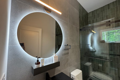 Bathroom - mid-sized contemporary gray tile and ceramic tile ceramic tile and single-sink bathroom idea in New York with a one-piece toilet, green walls, quartzite countertops and black countertops