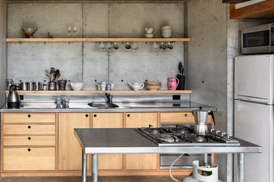 This is an example of a small industrial kitchen in Wellington with flat-panel cabinets, light wood cabinets, stainless steel benchtops and white appliances.