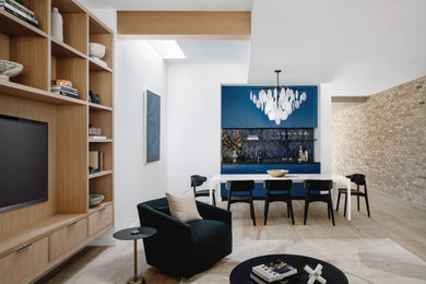 Trendy light wood floor, brown floor, exposed beam and brick wall living room photo in Austin with white walls and a media wall