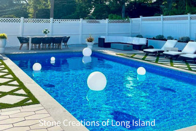 Diseño de piscina alargada minimalista grande rectangular en patio trasero con paisajismo de piscina y adoquines de hormigón