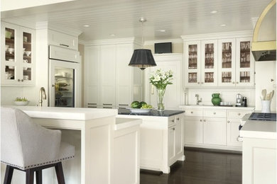 Enclosed kitchen - mid-sized traditional u-shaped dark wood floor enclosed kitchen idea in St Louis with shaker cabinets, white cabinets, solid surface countertops, white backsplash, stainless steel appliances and an island