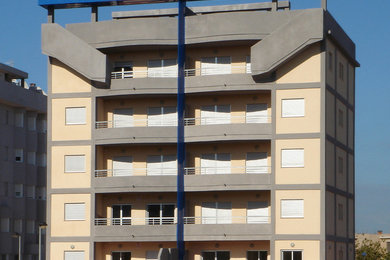 Modelo de fachada multicolor actual de tamaño medio de tres plantas con revestimiento de estuco y tejado plano