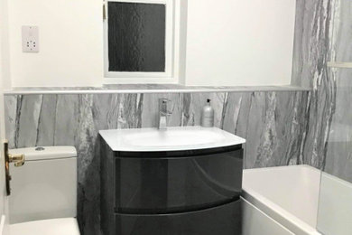 Inspiration for a contemporary family bathroom in Other with grey cabinets, a shower/bath combination, a built-in sink, grey floors, a hinged door, a single sink and a floating vanity unit.
