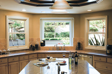 Inspiration for a mid-sized transitional u-shaped enclosed kitchen remodel in Portland with an undermount sink, raised-panel cabinets, light wood cabinets, granite countertops, beige backsplash, stone tile backsplash and an island