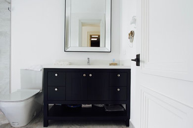 Trendy porcelain tile bathroom photo in Other with furniture-like cabinets, black cabinets, white walls and quartz countertops