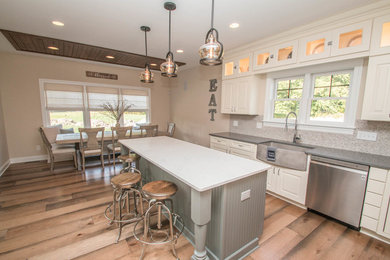 Inspiration for a large country u-shaped medium tone wood floor and brown floor eat-in kitchen remodel in Cleveland with a single-bowl sink, raised-panel cabinets, white cabinets, quartz countertops, multicolored backsplash, mosaic tile backsplash, stainless steel appliances, an island and white countertops